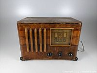 Front view of antique Emerson CS320 radio with wood casing, frequency dial, and control knobs.