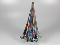 Front view of conical art glass paperweight shaped like a tree with colorful internal streaks and clear flared base edges.