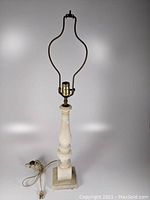 Full view of the alabaster table lamp showing the overall shape with square base, carved column, and metal socket with harp.