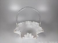 Side view of ruffled edge white silver crest pattern glass basket with clear handle