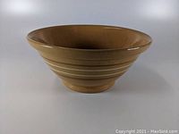Front side view of the large antique yellow ware pottery mixing bowl showing yellow glaze and horizontal rings.