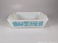 Front angled view showing turquoise blue Amish Butterprint design on white glass dish
