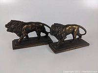 Pair of bronze lion bookends on white background showing side and front views.