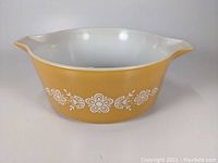 Front view of the yellow Pyrex Golden Butterfly 2.5 quart casserole dish with white floral butterfly pattern, showing the entire body of the dish.