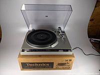Silver Technics SL-220 turntable on original box with clear dust cover open, power cord attached, missing the belt and cartridge.