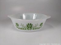 Image showing front side of vintage white milk glass casserole with green floral decoration and side handles.