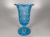 Front view of vintage ice blue footed vase showing lattice and thumbprint glass pattern with scalloped rim.