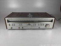 Front view of vintage Kenwood KR-710 receiver showing wood side panels and silver front with tuning dial, switches and knobs.