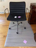Front view of black office chair on grey plastic mat on wood floor, showing full chair and mat size relative to hardwood floor