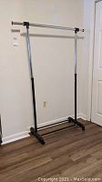 Front view showing full height clothes rack with adjustable horizontal bar and casters on black plastic base