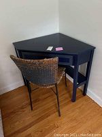 Corner desk and chair positioned in a corner against white walls, showing overall shape and setup