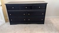 Front view of black painted dresser with 6 drawers on carpeted floor.