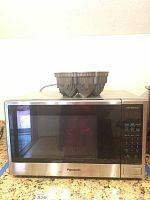 Front view of Panasonic stainless steel microwave with Bundt pan on top