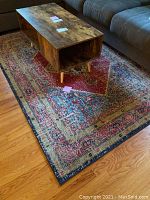 Full view of the multicolor patterned area rug on wooden floor with coffee table on top