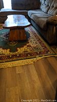 Living room setting showing the entire area rug placed under a wooden coffee table and sectional couch, revealing the overall size and shape.