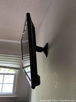 Side view of the TV mounted on wall bracket showing slim profile and mounting hardware.