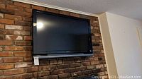 Sony 40-inch TV model KDL-40V4100 mounted on a brick wall, showing full front view.