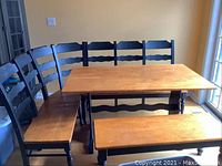 Full view of rectangular table with wooden top and black stained legs, L-shaped bench with black stained backrest in corner along two sides, and backless bench in front of table