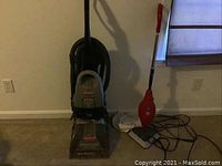 Image of Bissell PowerSteamer upright carpet cleaner and red Dirt Devil handheld steamer together on carpet.