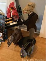 Wide view of the butler figure with tray, wooden rooster, and metal elephant on floor.