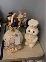 Five assorted decorative cookie jars on a tabletop showing Doughboy, carriage, pig, snowman, and fruit basket