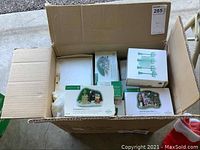 Open box with multiple Department 56 boxed items visible including The Charitable Vicar and green lamp posts.