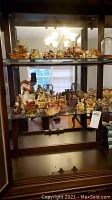 Wide view of two glass shelves filled with Harmony Kingdom figurines in a display cabinet
