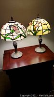 Pair of two 20-inch Tiffany-style stained glass table lamps on a wooden table, showing full lamps and design
