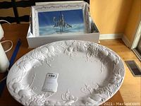 Photo showing the large white ceramic serving platter with embossed grapevine and fruit design on rim