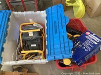 Two plastic bins, one white holding three portable shop lights and extension cords, another red holding spray tool box and bike pump.