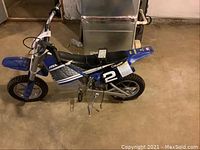 Side view of blue Razor MX350 child's electric bike showing number 2 decal and knobby tires.