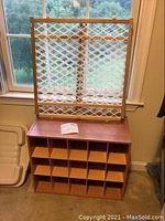Full view of shoe cubby topped with small wood baby gate leaning against window.