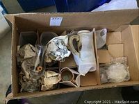 Photo showing a cardboard box containing the beer glasses and a ceramic beer stein wrapped carefully with fabric and paper.