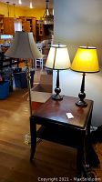 Photo of 1 floor lamp and 2 table lamps placed on and beside a wooden side table.