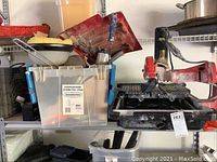 Photo showing the Husky tile saw on shelf alongside a clear plastic bin containing partial driver set and other small tools.