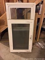 Three white casement windows leaning against wall, one window with handle hardware visible on front.