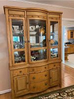 Full view of wood china cabinet with glass doors and dishes inside.