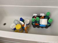 Full view of all cleaning and disinfectant products arranged in a bathtub, showing bottles, spray cleaners, disinfecting wipes, and other assorted products.