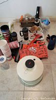 Photo showing entire collection of items including paper cups, plastic cups, salt and pepper shakers, electric wine opener, Brita water pitcher, chip clips, reusable bags, knives, and a salad spinner.