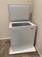 Closed white chest freezer showing front and top with lid open slightly.