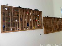 Two wooden printers drawers mounted on a wall, each filled with various miniatures including ceramic and glass items as well as miniature vehicles.