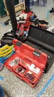 Photo showing the red Craftsman plastic toolbox open with small tools and screws inside, along with nearby leaf blower and other tools on garage floor.