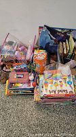 Wide view of toys and games lot including Play-Doh, board games, sand art kit, markers, and coloring books