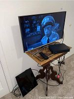 Samsung 32-inch TV powered on displaying black and white image with TV remote and antenna on table beside TV.