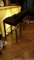 Side view of three stools at bar showing upholstered seats and bolster backs