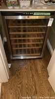 Front view of stainless steel framed glass door bar fridge on wood floor