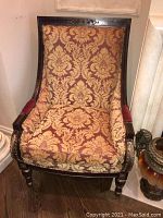 Front view of one chair showing damask upholstery and carved wood frame