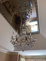 Full view of chandelier suspended below mirrored ceiling
