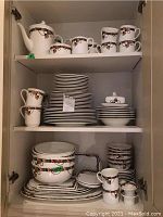 Three shelves of china with assorted plates, bowls, cups and serving pieces