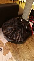 Overall top view of round brown cushion on hardwood floor with surrounding furniture